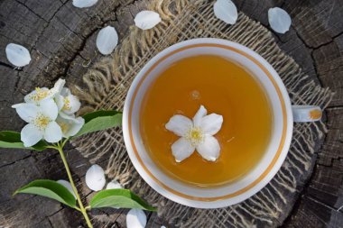 Yasemin çiçekleri ve ahşap arka plan ve çuval üzerinde taze çay.