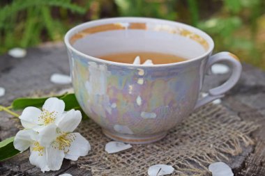 Yasemin çiçekleri ve ahşap arka plan ve çuval üzerinde taze çay.