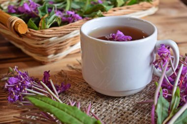 Traditional Russian herbal drink. Ivan-tea in a Cup close-up on a wooden table. It has a positive effect on the human body. clipart