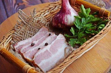 Ahşap arka plan üzerinde baharat, otlar ve sarımsak ile lezzetli füme pastırma.