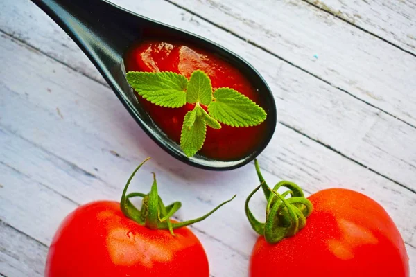 Tomato paste with ripe tomatoes on a wooden table.