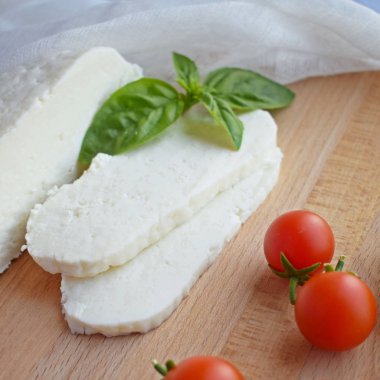 Ahşap tahta üzerinde yatan ev yapımı dilimlenmiş Adyghe peyniri.