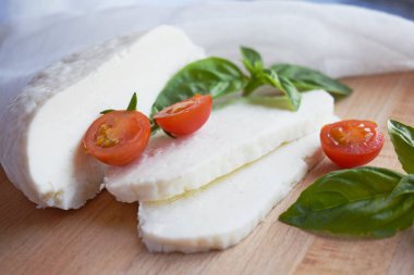 Ahşap tahta üzerinde yatan ev yapımı dilimlenmiş Adyghe peyniri.