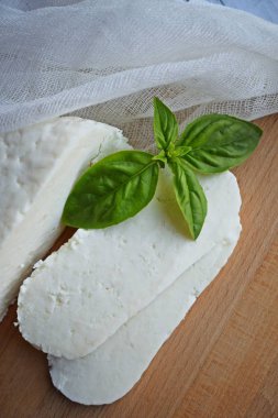 Ahşap tahta üzerinde yatan ev yapımı dilimlenmiş Adyghe peyniri.