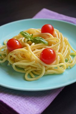 Siyah bir arka plan üzerinde otlar ve domates ile Lezzetli spagetti.