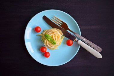 Siyah bir arka plan üzerinde otlar ve domates ile Lezzetli spagetti.