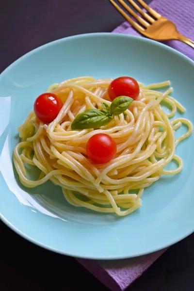 Siyah bir arka plan üzerinde otlar ve domates ile Lezzetli spagetti.