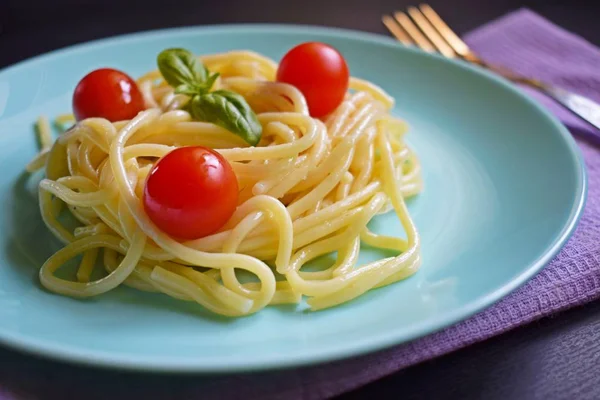 Siyah bir arka plan üzerinde otlar ve domates ile Lezzetli spagetti.