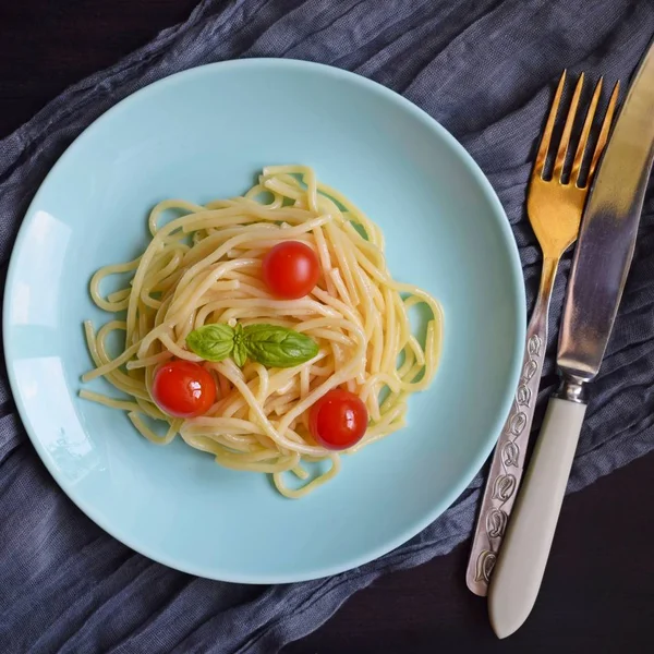 Siyah bir arka plan üzerinde otlar ve domates ile Lezzetli spagetti.