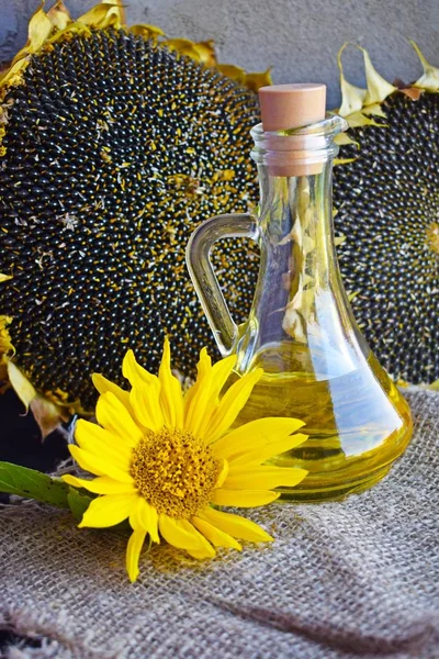 Sunflower oil, sunflower flowers and ripe seeds on a background of burlap.
