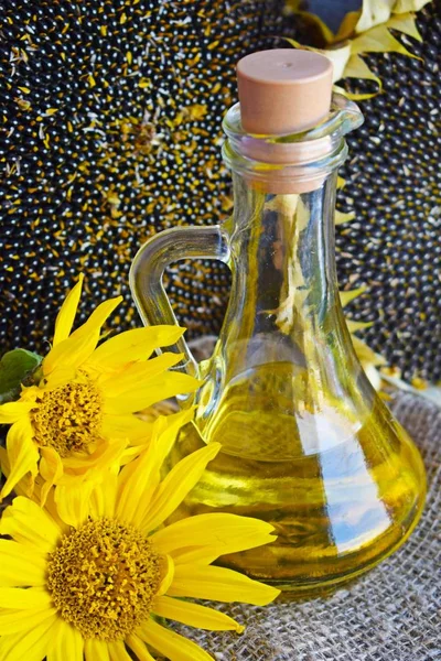 Sunflower oil, sunflower flowers and ripe seeds on a background of burlap.