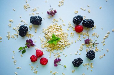 Ham yulaf ezmesi ve taze ahududu ve böğürtlen mavi bir arka plan üzerinde. Sağlıklı gıda.
