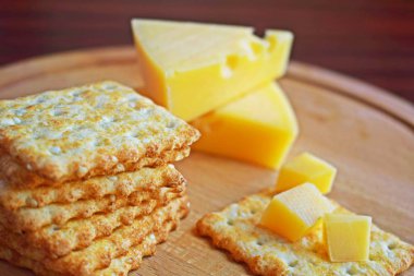 Ahşap arka planda peynir ve susam ile taze gevrek kraker.