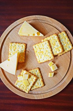 Ahşap arka planda peynir ve susam ile taze gevrek kraker.