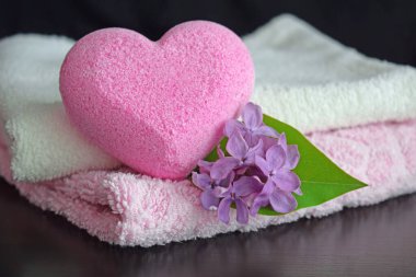 Leylak kokulu hafif bir kalp şeklinde banyo tuzu. Çoğunlukla havlular ve siyah arka planda bir çiçek..