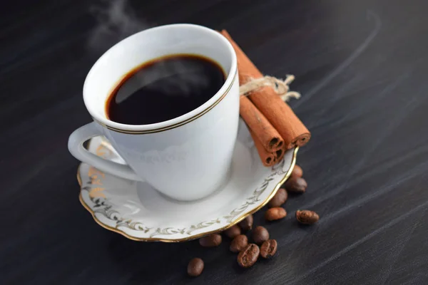 在黑色背景上的一杯香浓的咖啡和肉桂 — 图库照片
