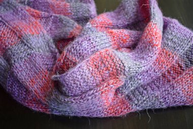 Siyah arka planda yün iplikten yapılmış leylak çizgili eşarp..