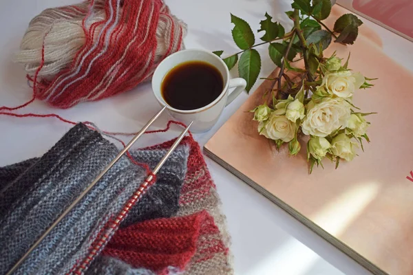 Bir fincan mis kokulu kahve ve beyaz bir arka planda örgü iğneleriyle örülmüş bir eşarp..