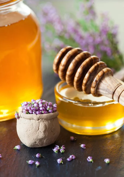 新鮮な天然蜂蜜 木製蜂蜜ディッパーおよび茶色のテーブルの上のヘザーの花の美しい構図 — ストック写真