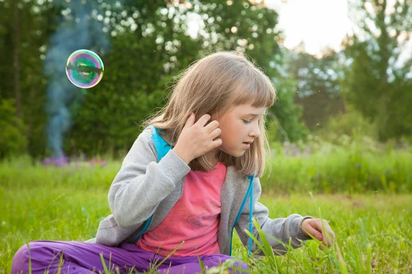 夏の公園で座っているシャボン玉と遊ぶかわいい幼児女の子 — ストック写真