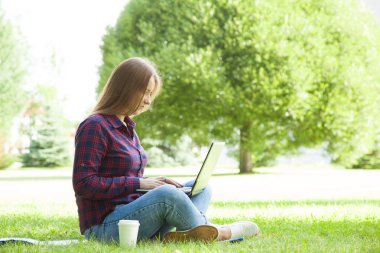 Bir dizüstü bilgisayar bir yaz parkta oturan çekici öğrenci kız