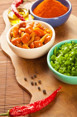 Malzemeler ahşap bir gemide yemek güzel kompozisyon: Marine tatlım agarics, kıyılmış yeşil soğan, biber biber, zeytinyağı, baharat