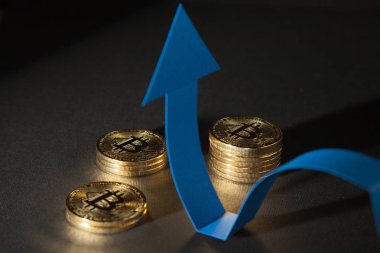 Parlak bitcoins ve pozitif eğilim, siyah arka plan gösteren gösterilen mavi ok