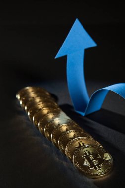 Parlak bitcoins ve pozitif eğilim, siyah arka plan gösteren gösterilen mavi ok