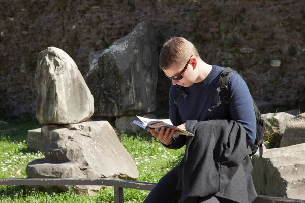 Jovem Homem Bonito Lendo Guia Turístico Sentado Livre — Fotografia de Stock