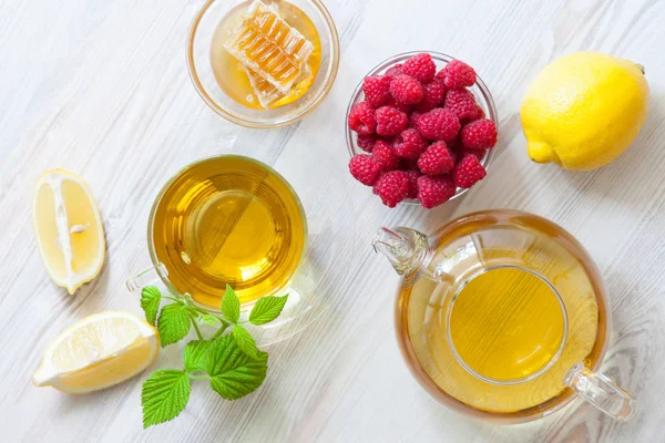 Composition of natural remedies for fast recovery: honey, fresh raspberreis, herbal tea and lemon; upper viewpoint