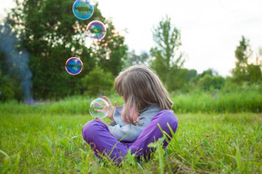 Sabun köpüğü çimlere oturup oynamaktan tanınmayan küçük kız