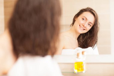 Gülümseyen genç kadın saçları havluyla siliyor