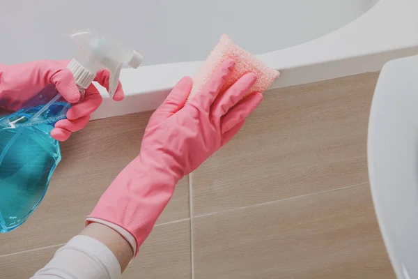 Pembantu di sarung tangan karet membersihkan kamar mandi dengan spons — Stok Foto