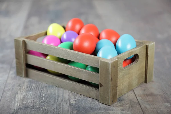 Multicoloured Easter eggs in a wooden box — Stock Photo, Image