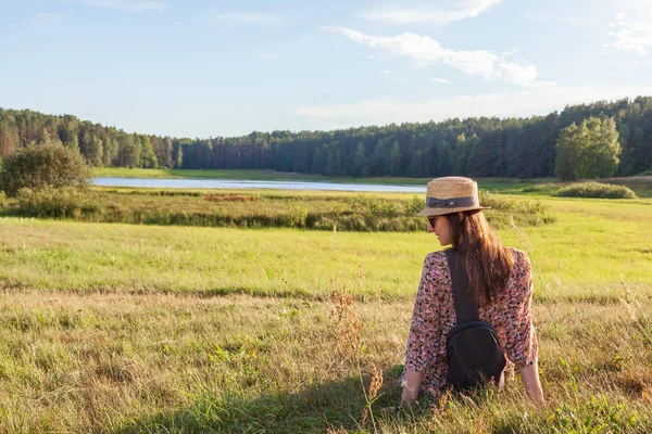 年轻女子在帽子享受迷人的风景坐在田野上 — 图库照片