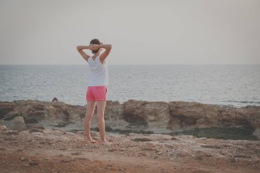 Genç kadın sabah denize yakın egzersizleri yapıyor