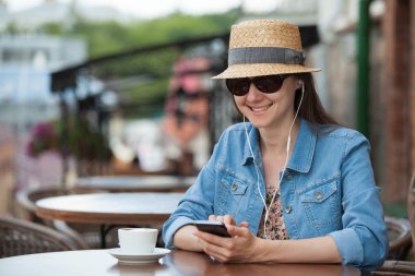 Sokak kafede telefonda konuşurken kahve fincan ile büyüleyici genç kadın.