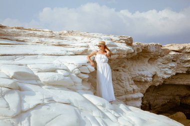 Deniz, Kıbrıs 'ta beyaz uçurumda poz elbise giyen büyüleyici genç kadın.