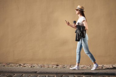 Kahve ve cep telefonu fincan açık havada yürüyüş genç kadın