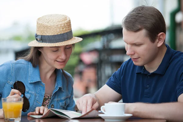 Young couple planning journey on map at cafe