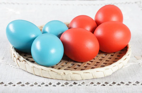Цветные пасхальные яйца на плетеной соломенной подставке — стоковое фото