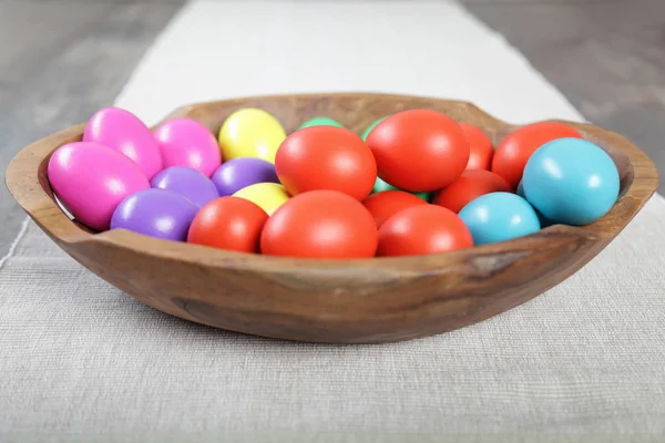 Multicoloured Easter eggs in a large wooden bowl — Stock Photo, Image