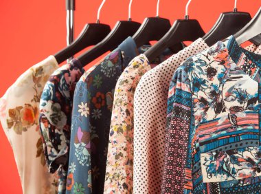 Trendy kadınsı giysiler kırmızı arka planda üst üste asmak
