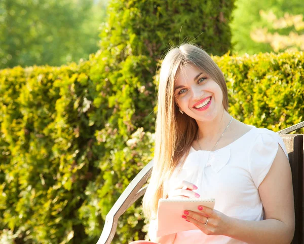 Щаслива Усміхнена Молода Жінка Пише Блокноті Сидячи Літньому Парку — стокове фото