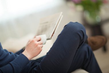 Tanınmayan işadamı sabah gazetesi okuyarak kahve fincanı ile rahat poz oturuyor