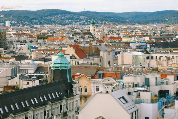 Viyana ufuk çizgisinin manzaralı panoramik manzarası güneşliğin altında Viyana etrafındaki yüksek tepelerin manzarasıyla şehir çatıları inşa ediyor. — Stok fotoğraf