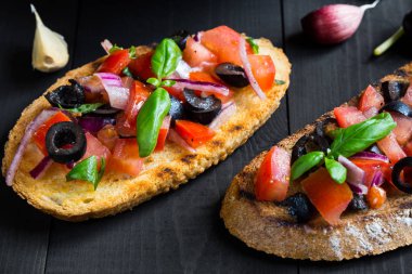 Bruschetta domates ve fesleğen siyah ahşap kurullarında.