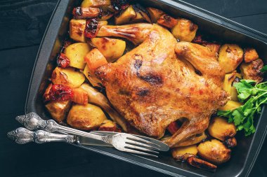 Fried chicken sebze siyah ahşap zemin ile. Sonraki eski çatal ve bıçak. Üst tonda görünümünün.