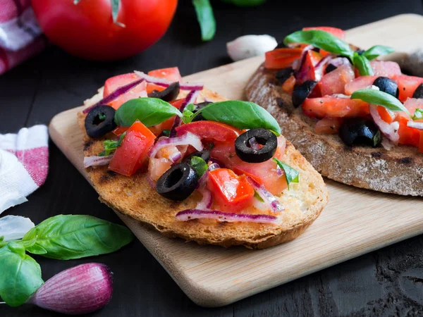 Bruschetta domates ve fesleğen siyah ahşap kurullarında.