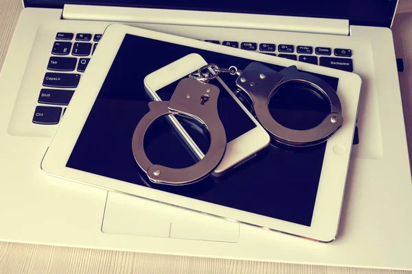 Kelepçe (dizüstü bilgisayar, yastık, telefon) elektronik cihazlarda. Ağdaki suçların cezası. Tonda fotoğraf.
